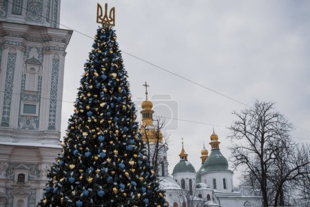 Photo for KYIV, UKRAINE  DECEMBER 6, 2023: THE COUNTRY'S MAIN TREE WAS INSTALLED ON SOFIVSKA AQUARE, WHICH WAS OFFICIALLY LIGHTED IN THE EVENING ON NICHOLAS DAY. PEOPLE ARE ALREADY WALKING NEAR HER - Royalty Free Image