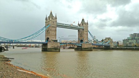 Foto de Vista panorámica del Puente de la Torre y el río Támesis en la ciudad de Londres con la orilla del mar a la izquierda-abajo, en un día nublado. - Imagen libre de derechos