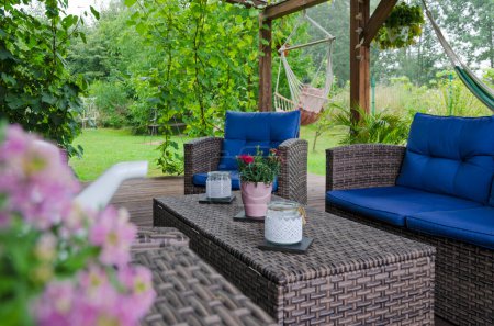 Téléchargez les photos : Belle terrasse couverte avec jardin verdoyant et bois naturel, meubles en rotin, hamac. Été extérieur et se détendre dans le patio. - en image libre de droit