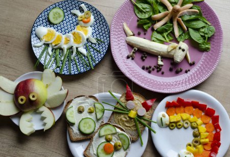 Healthy meal with vegetables and fruit for children on breakfast. Fun food and creative dish in the morning. Colorful eating on a table.