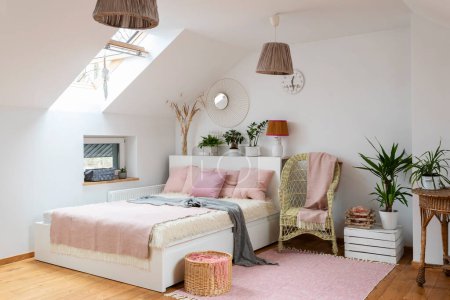 Photo for Cozy bedroom with doble bed and pink decoration in the attic. White wall, design lamp and wooden floor in room at home. - Royalty Free Image