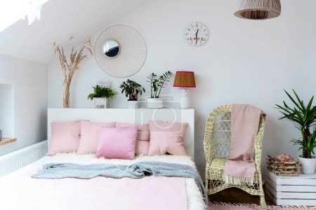 Foto de Luminoso interior del dormitorio en el ático con cama doble, almohadas rosas y suelo de madera. Diseño escandinavo y relax en el hotel. - Imagen libre de derechos