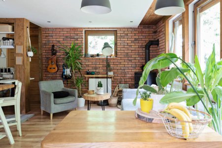 Photo for Interior of cozy living room in rural cottage. Brick wall, wooden floor and comfortable armchair in design indoor with window. - Royalty Free Image