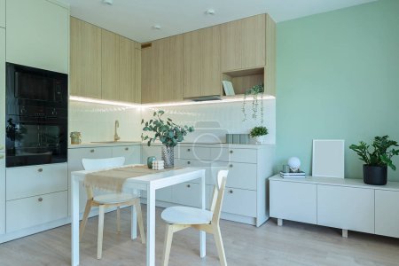 Foto de Lujosa cocina con muebles modernos, horno, mesa y sillas en un elegante interior. Arquitectura de diseño nuevo en apartamento. - Imagen libre de derechos