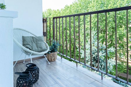 Photo for Balcony with barrier with comfortable armchair and pillow and green greenery. Outdoor place for relaxation. Lifestyle and nobody. - Royalty Free Image