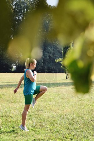 Téléchargez les photos : Jogging femme pratique la formation dans un parc à l'extérieur.Gymnastique pour la santé et le corps flexible. Fille coureuse pleine d'énergie et d'activité. Vertical. - en image libre de droit