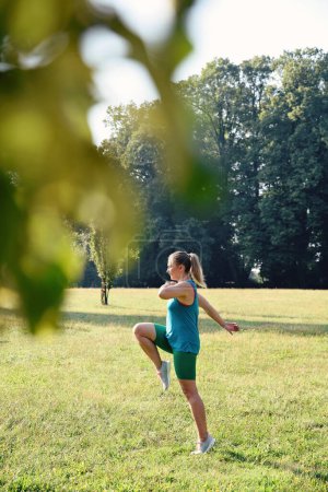 Téléchargez les photos : Jogging femme pratique la formation dans un parc à l'extérieur.Gymnastique pour la santé et le corps flexible. Fille coureuse pleine d'énergie et d'activité. Vertical. - en image libre de droit