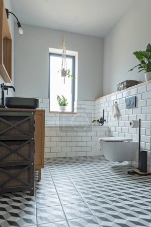 Téléchargez les photos : Salle de bains avec fenêtre dans un intérieur moderne dans un appartement design. Sol avec carreaux de texture, toilettes élégantes et lavabo noir. - en image libre de droit