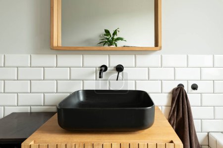 Photo for Industrial interior of bathroom with black ceramic washbasin on wooden cabinet, square mirror and white tiles on the wall. - Royalty Free Image