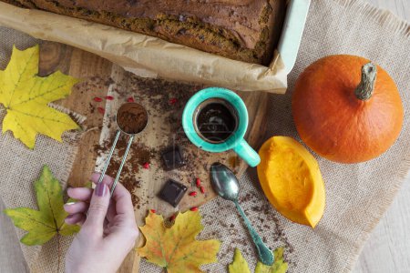 Téléchargez les photos : Nourriture d'automne au déjeuner avec du pain de citrouille et des feuilles jaunes sur une table en bois. Dessert fait maison avec café et main de femme dans la cuisine. Vue du dessus - en image libre de droit