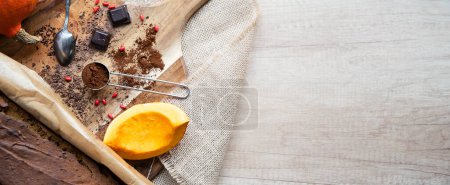 Photo for Pan of chocolate baking made from pumpkin, cocoa and coffee on the wooden table in the kitchen with copy space. Brown natural background panoramic banner. - Royalty Free Image