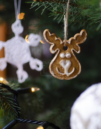 Téléchargez les photos : Carte de Noël avec décoration de Noël sur une branche de sapin. Vacances et temps d'hiver avec des rennes en pain d'épice doux. Vertical. - en image libre de droit