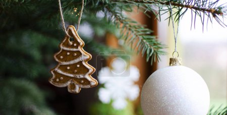 Foto de Árbol de Navidad con decoración, pan de jengibre casero dulce y bola de Navidad blanca. Invierno y celebración con rama verde de pino. De cerca. Banner - Imagen libre de derechos
