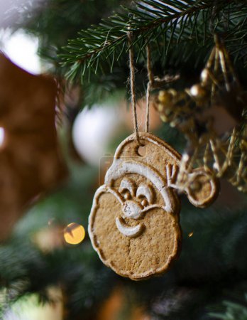 Foto de Decoración de Navidad de pan de jengibre Santa Claus colgando del árbol de Navidad con luces bokeh. Diciembre y días festivos. Vertical - Imagen libre de derechos