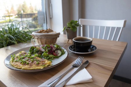 Téléchargez les photos : Repas végétarien pour un petit déjeuner sain le matin au restaurant. Omelette avec salade et café noir. Nourriture savoureuse. - en image libre de droit