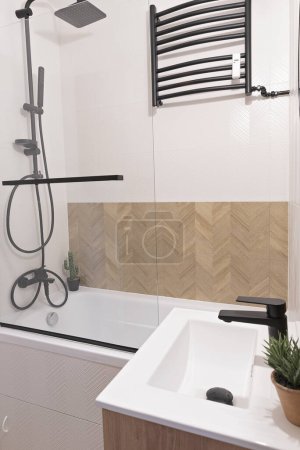 Téléchargez les photos : Petite salle de bain dans un style moderne avec des carreaux de motif chevrons sur le mur et évier en céramique avec robinet dans un intérieur élégant. - en image libre de droit