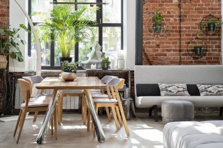 Photo for Industrial bright interior of living room in loft apartment in modern style. Bricky wall, big window and wooden table in luxurious style. - Royalty Free Image