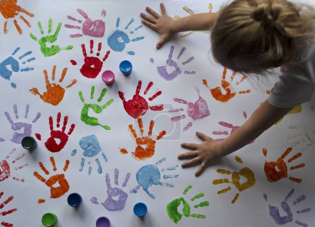 Téléchargez les photos : Peinture d'enfant avec les mains et les empreintes de main colorées. Créativité et artisanat à la maternelle. Jeu sensoriel et petite fille. - en image libre de droit
