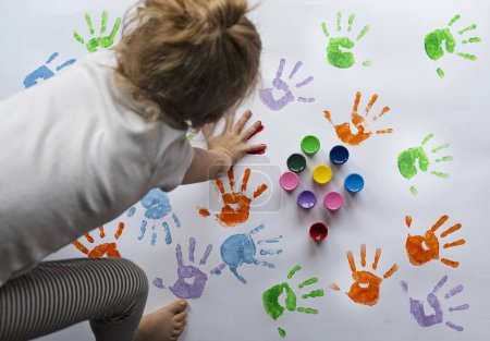 Téléchargez les photos : Empreinte à la main et empreinte par l'enfant dans des couleurs différentes sur papier blanc. Fun, éducation et jeu sensoriel. Reste à la maison avec Childen. Créativité et art - en image libre de droit