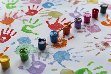 Photo for Hand prints in different color on white background with paints and brush. Colorful nhand print of little child. Education, play and fun. Art in kindergarten. - Royalty Free Image