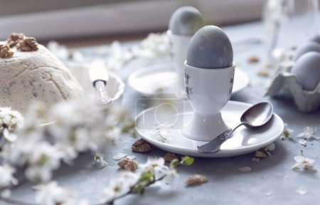 Foto de Huevos de Pascua en un plato con cuchara y flor blanca de primavera en la mesa decorativa durante el desayuno de Pascua. Tarjeta de Pascua en estilo vintage. De cerca.. - Imagen libre de derechos