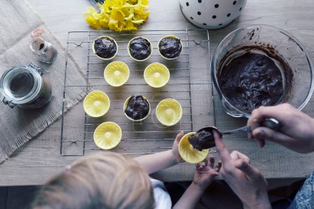 Téléchargez les photos : Délicieuse recette de muffins maison sains pour Pâques. Préparer la pâtisserie pour le dessert au chocolat. Temps en famille avec cuisson avant Pâques. Fleurs jaunes sur une table dans la cuisine. Vue du dessus. - en image libre de droit