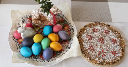 Foto de Mesa de Pascua con huevos coloridos, conejito de Pascua y pastel dulce. Huevos coloreados y pintados para la celebración tradicional. - Imagen libre de derechos