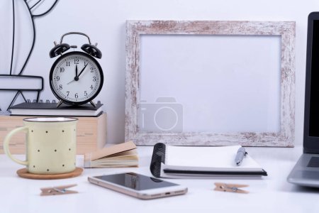 Photo for White office desk with blank frame for write, coffee, clock, and laptop for work. Business and technology during home office. - Royalty Free Image