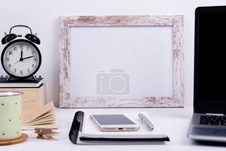 Photo for White office desk with blank frame for write, coffee, clock, and laptop for work. Business and technology during home office. - Royalty Free Image