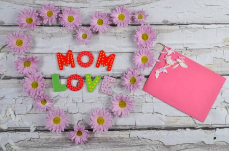 Téléchargez les photos : Carte de fête des mères pour les salutations avec coeur à base de fleurs roses sur fond en bois. Vacances et amour. - en image libre de droit