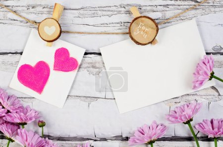 Téléchargez les photos : Carte de voeux vierge avec des fleurs et des cœurs peints sur fond blanc en bois. Maquette et fête des mères. - en image libre de droit