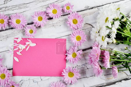Foto de Tarjeta de felicitación para el día de la madre con corazón hecho de flores y papel blanco rosa sobre fondo de madera. Vista superior. - Imagen libre de derechos
