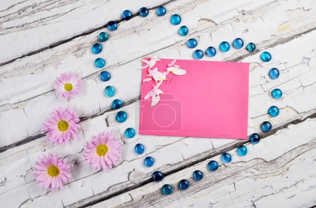 Téléchargez les photos : Carte de vœux le jour de la fête des mères avec un papier rose avec maquette, et coeur en forme sur un fond en bois avec des fleurs. - en image libre de droit