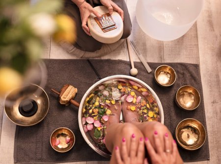 Photo for Female feet at spa salon with sound healing. Legs of woman in bowl with flowers and petals of rose. Massage and pedicure. Relax - Royalty Free Image