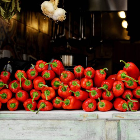 Téléchargez les photos : Pile de poivrons rouges crus sur le comptoir en bois du marchand de légumes à l'extérieur. Sguare - en image libre de droit