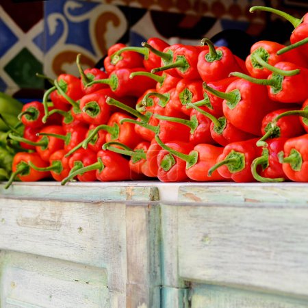 Photo for Red peppers on the wooden display in the greengrocer. Fresh raw vegetables for sale. Square. - Royalty Free Image