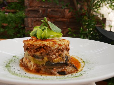 Téléchargez les photos : Moussaka comme plat traditionnel grec pour le dîner sur une assiette blanche au restaurant. Repas à base d'aubergine et de viande au four. Prêt à manger. Gros plan. - en image libre de droit
