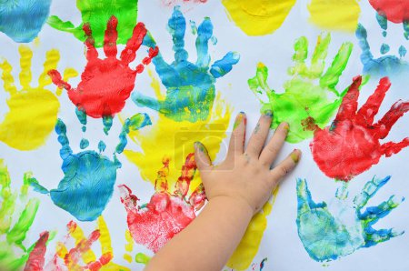 Téléchargez les photos : Empreinte de main multicolore de petite fille sur le fond blanc. Fun pour enfant avec créativité et concept artistique. - en image libre de droit
