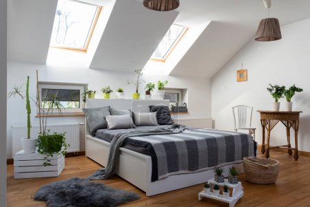 Foto de Amplio interior de dormitorio con una gran cantidad de plantas y almohadas grises. Diseño escandinavo. - Imagen libre de derechos