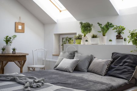 Téléchargez les photos : Intérieur de la chambre dans le grenier avec mobilier blanc et lit double avec oreillers dans un design scandinave - en image libre de droit
