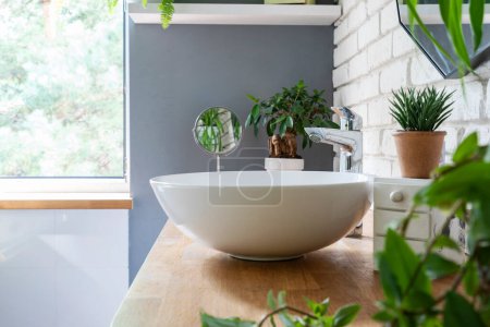 Téléchargez les photos : Spa moderne avec fenêtre et plantes vertes et plantes en pot et lavabo en céramique. Intérieur de la salle de bain avec mur de briques dans un style industriel. - en image libre de droit