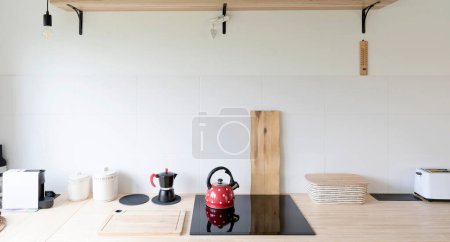 Kitchen interior with white tiles and wooden counter in rural style. Scandinavian interior with kitchenware, electric hob and modern design. Bright indoor in apartment. Panoramic banner.