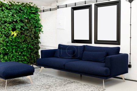 Foto de Interior de la sala de estar con sofá moderno y marco de imagen con maqueta en la pared. Jardín vertical en apartamento loft. - Imagen libre de derechos