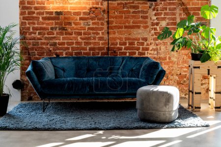 Téléchargez les photos : Canapé marine dans le salon avec des plantes et un fond mural en brique. Intérieur moderne. - en image libre de droit