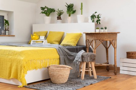Téléchargez les photos : Intérieur de la chambre dans le style boho avec lit avec oreillers jaunes et couverture. Design scandinave dans la chambre à la maison confortable. - en image libre de droit