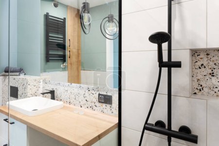 Foto de Elegante cuarto de baño con lavabo de cerámica en el mostrador de madera, espejo en la pared y ducha moderna. Interior del baño. Hotel. - Imagen libre de derechos