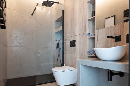 Téléchargez les photos : Modern bathroom with stylish bowl on the counter with faucet and modern shower with glass. Luxurious interior of room with grey granite tiles on the wall in loft style. - en image libre de droit