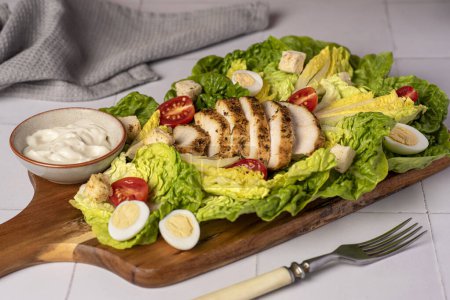 Téléchargez les photos : Photographie culinaire de salade de césar avec poulet frit, laitue romaine, oeufs de caille, tomate, croûtons, sauce - en image libre de droit