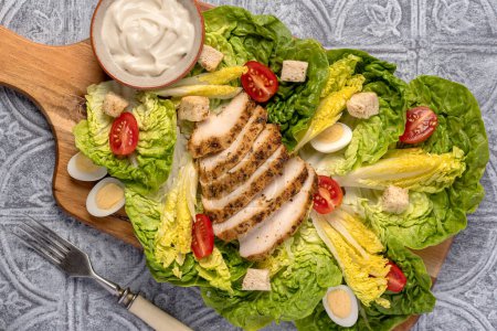 Photo for Food photography of caesar salad with fried chicken, lettuce romaine, quail eggs, tomato, croutons, sauce - Royalty Free Image