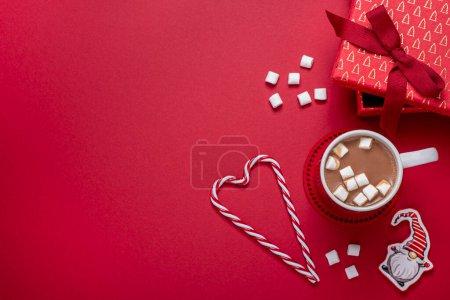 Foto de Fotografía de fondo rojo de cosas de Navidad, caja de regalo, cacao, taza, malvavisco, gnomo, caramelo, en blanco, espacio para copiar, tarjeta, invitación - Imagen libre de derechos